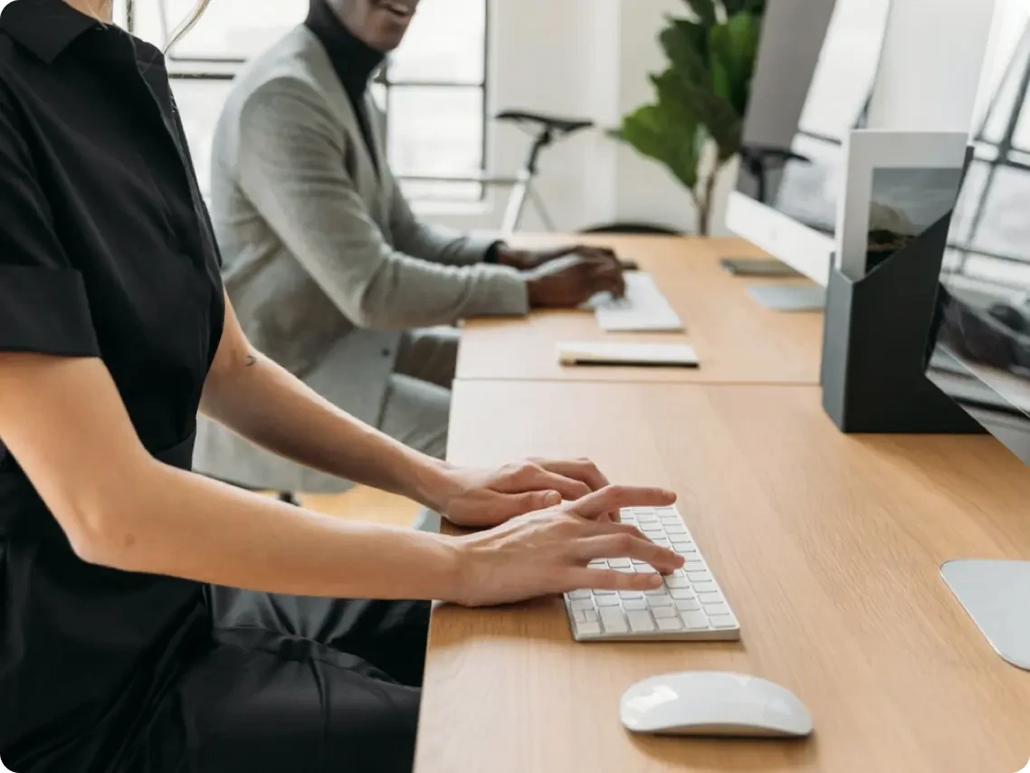 two people typing at a desk